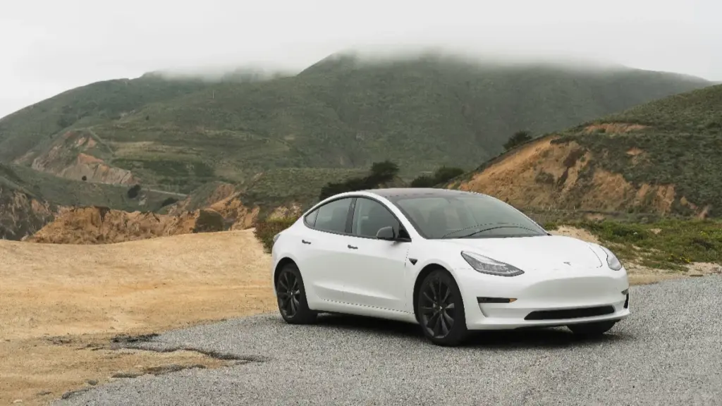 a white sedan parked beside the mountain