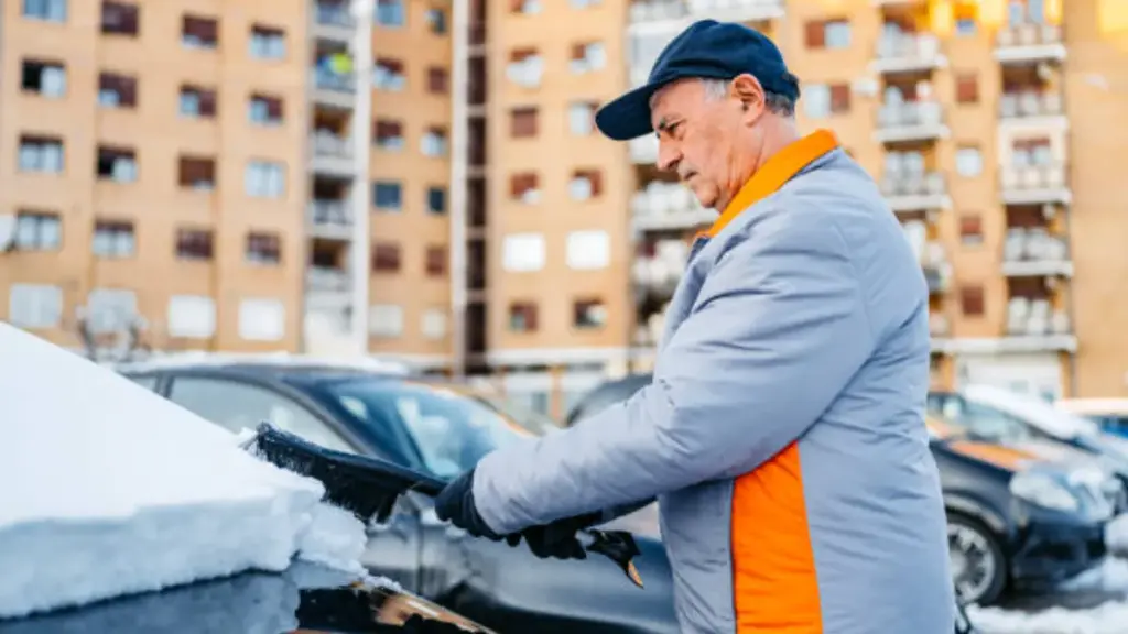 senior man clear snow on the windshield