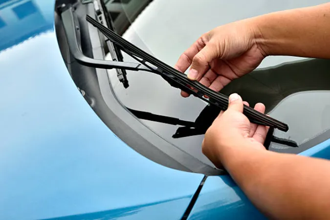 Man hand picking up windscreen wiper blade