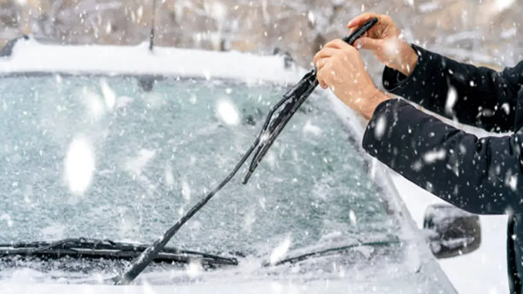 Man adjusting and cleaning wipers of car in snowy weather