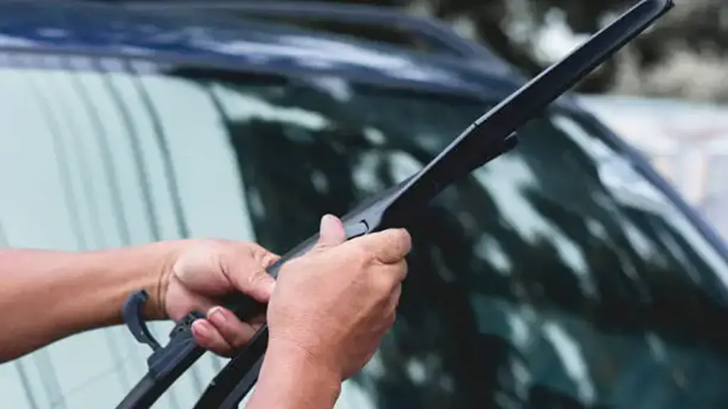 Mechanic replace windshield wipers on car